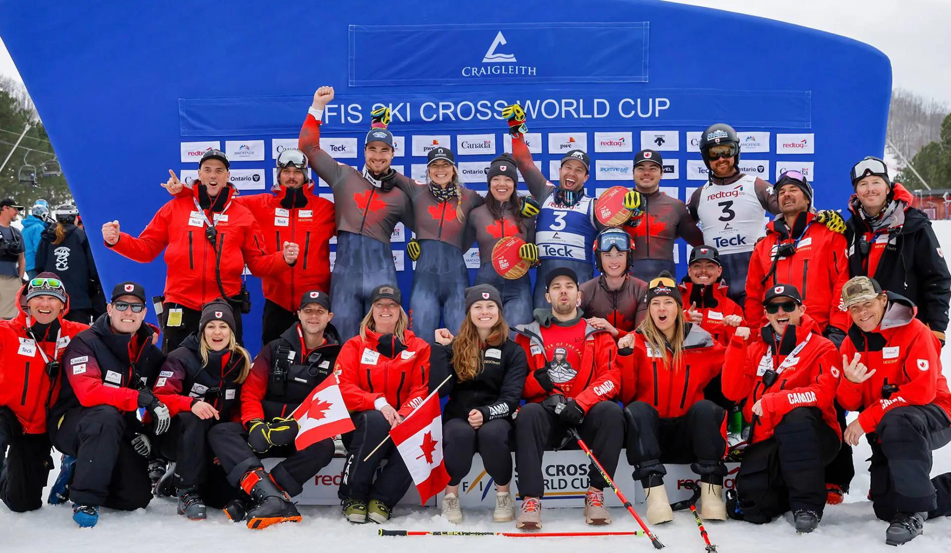 The team celebrate together with Canadian flags in a wide group shot