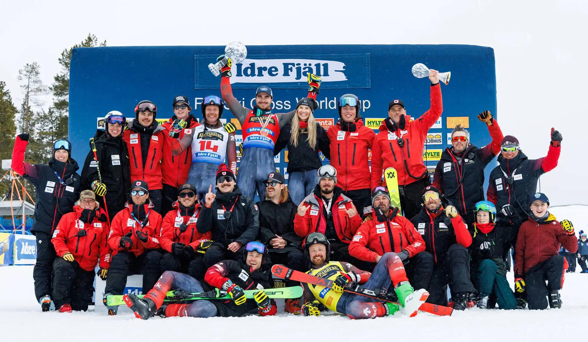 a group shot of skiers celebrating together in the snow with their trophies