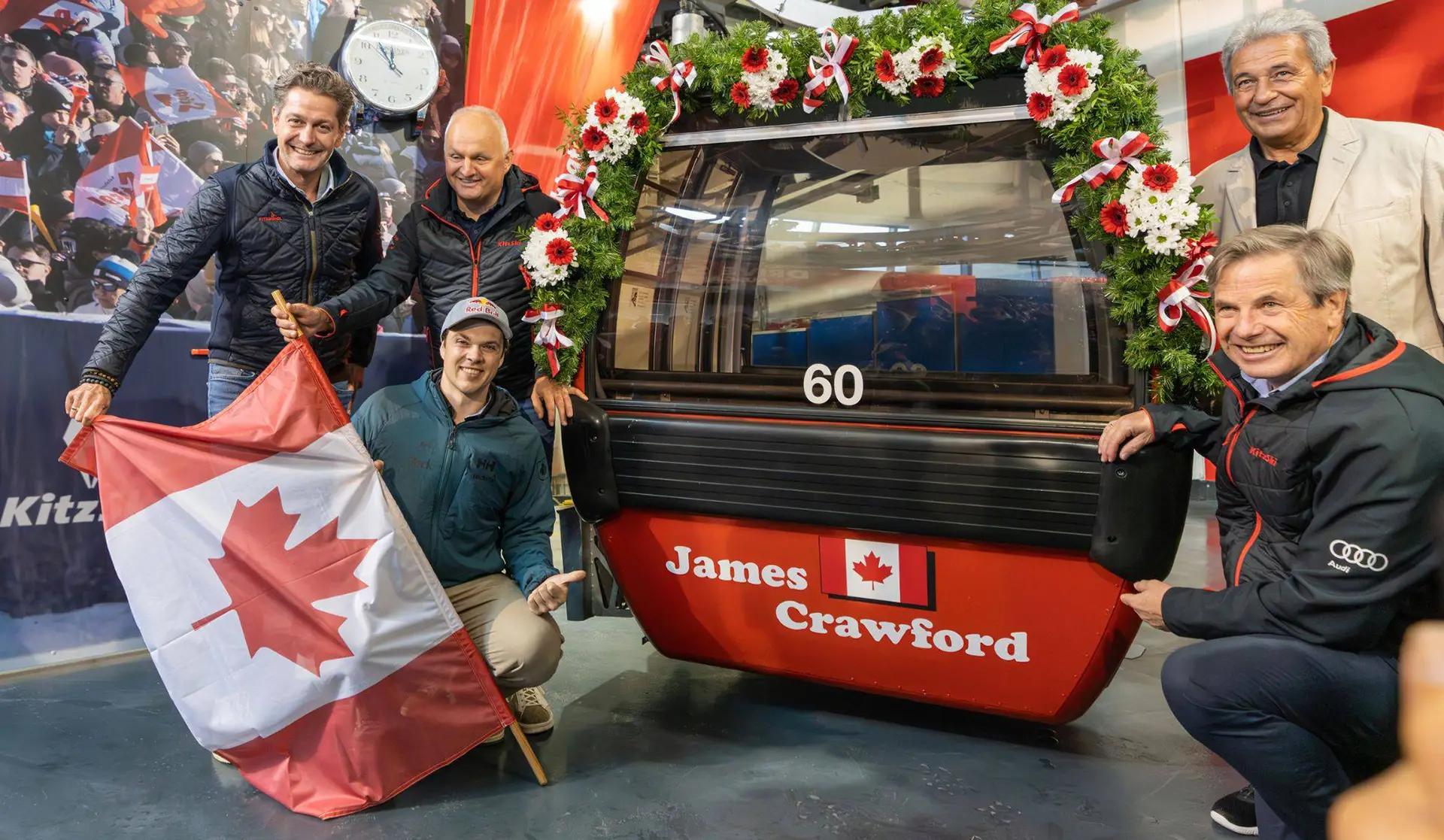 James Crawford avec d'autres personnes devant la cabine qui porte son nom
