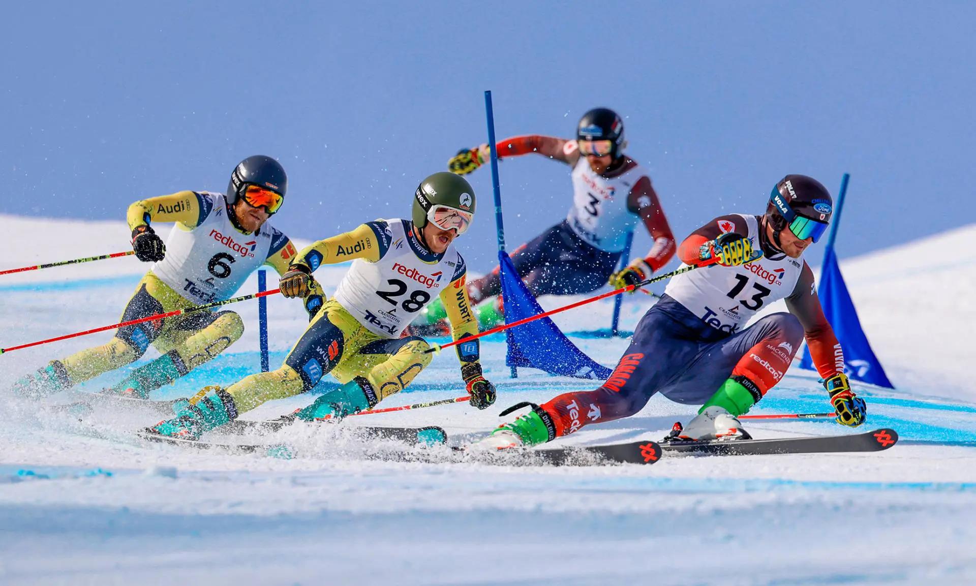 Une photo d'action de 4 skieurs en course, effectuant un virage