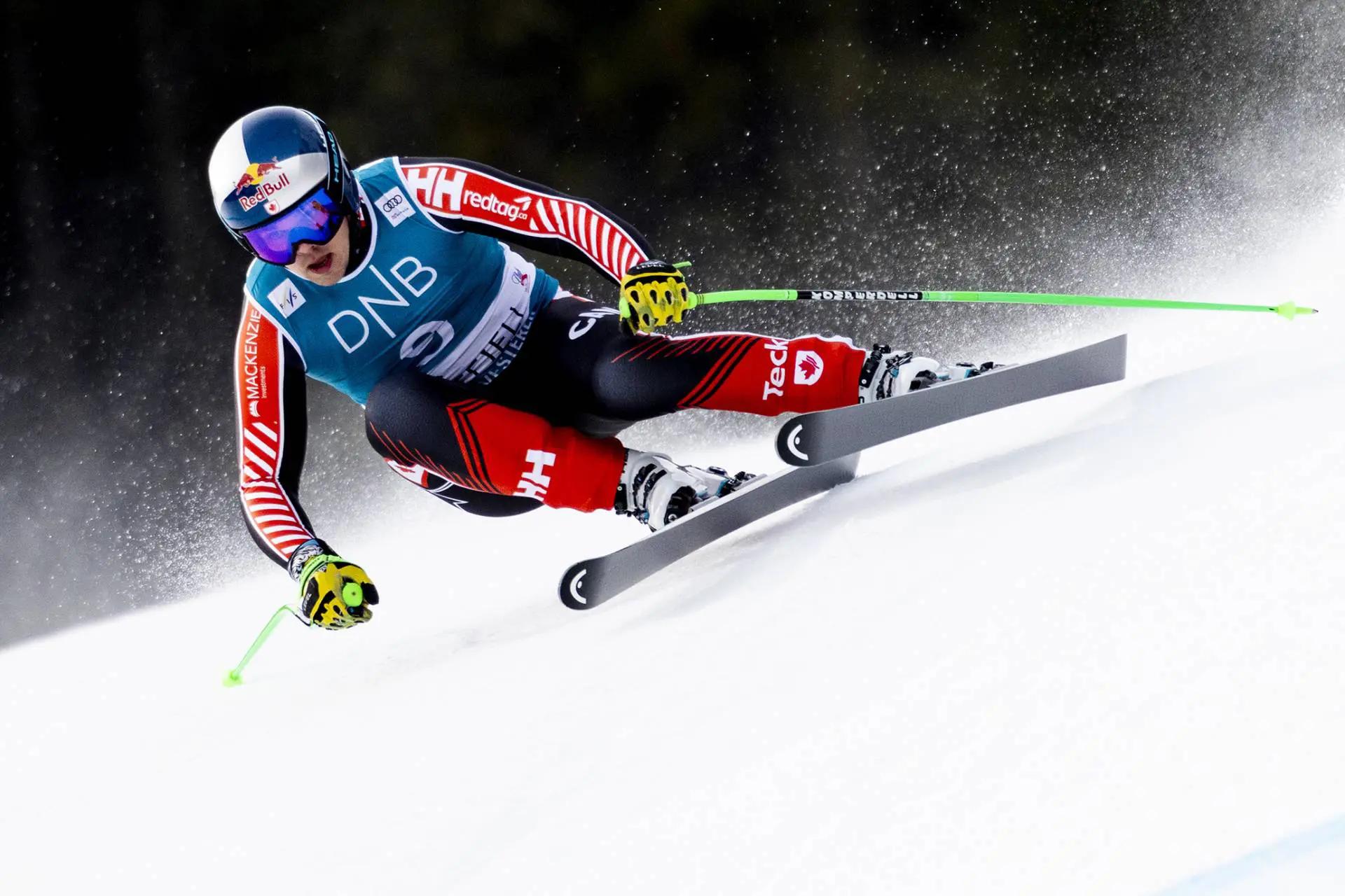 An action shot of James Crawford skiing down the slope, with snow particles spraying in the air